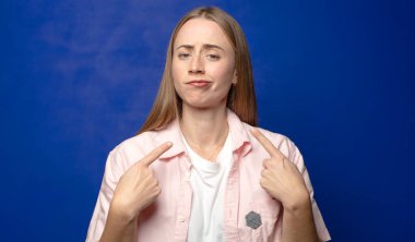 Kibirli ve agresif görünen, yukarıyı gösteren ya da ellerinle alay eden bir tavır takınarak.