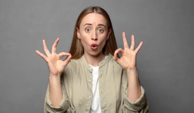 Şaşırmış, şaşırmış ve şaşırmış hissediyorsun. Onayladığını gösteriyorsun. İki elinle de onay imzası atıyorsun.