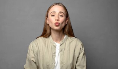 Sevimli, eğlenceli, mutlu, sevimli bir yüz ifadesiyle dudakları birbirine bastırmak, öpücük göndermek.