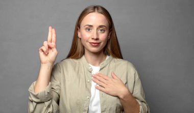 Mutlu, kendinden emin ve güvenilir görünüyor, gülümsüyor ve olumlu bir tavırla zafer işareti gösteriyor.