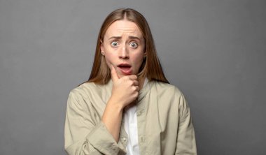 Ağzı ve gözleri açık ve elleri çenesinde, nahoş bir şekilde şokta, ne diyor ya da vay be