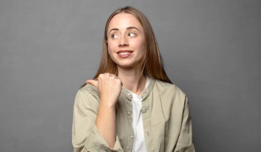 Neşeli bir şekilde gülümsüyor ve yan taraftaki fotokopi alanını işaret ediyor, mutlu ve tatmin olmuş hissediyordu.