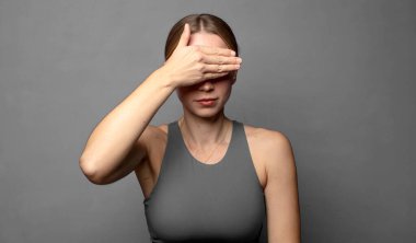 Bir eliyle gözlerini kapatan korkmuş ya da endişeli hisseden, merak eden ya da körü körüne bir sürpriz bekleyen. fitness konsepti