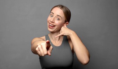 Neşeli bir şekilde gülümsüyor ve kamerayı işaret ediyor. Daha sonra seni arıyor, telefonla konuşuyor. fitness konsepti