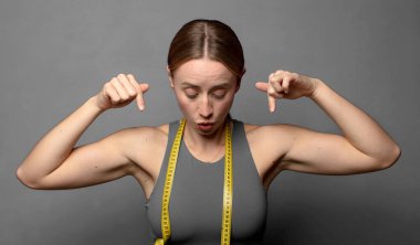 İki eliyle aşağıya doğru bakan ağzı açık, şaşkın, şaşkın ve şaşırmış bir şekilde bakıyor. fitness konsepti