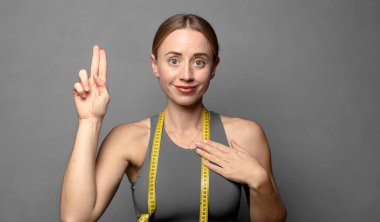 Mutlu, kendinden emin ve güvenilir görünüyor, gülümsüyor ve olumlu bir tavırla zafer işareti gösteriyor. fitness konsepti