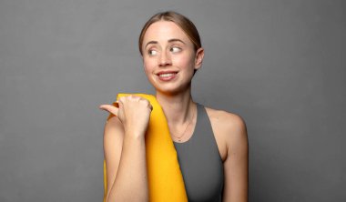 Neşeli bir şekilde gülümsüyor ve yan taraftaki fotokopi alanını işaret ediyor, mutlu ve tatmin olmuş hissediyordu. fitness konsepti