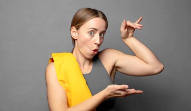 Neşeli ve şaşırmış hissediyorum, şok olmuş bir ifadeyle gülümsüyorum ve bir şey tutuyorum. fitness konsepti