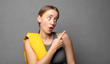 Neşeli ve şaşırmış hissediyorum, şok olmuş bir ifadeyle gülümsüyorum ve bir tarafı işaret ediyorum. fitness konsepti