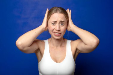 Sarışın kadın kendini stresli, endişeli, endişeli ya da korkmuş hissediyor. Elleri başının üstünde, hatayla panikliyor.