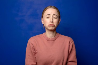 Sarışın kadın üzgün ve mızmızlanıyor, mutsuz bir bakışla, negatif ve hayal kırıklığına uğramış bir tavırla ağlıyor.