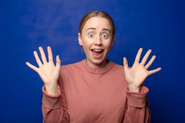 Sarışın kadın mutlu ve heyecanlı görünüyordu. Beklenmedik bir sürprizle şoke olmuştu. İki eli yüzü açıktı.