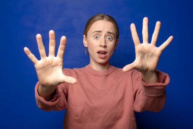 Sarışın kadın sersemlemiş ve korkmuş hissediyor. Korkutucu bir şeyden korkuyor. Elleri açık ve uzak dur diyor.