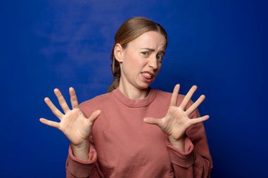 Sarışın kadın tiksinti ve tedirginlik duyuyor, dilini dışarı çıkarıyor, iğrenç ve iğrenç bir şeyden hoşlanmıyor.