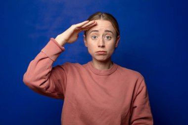 Sarışın kadın kameraya askeri bir selamlama ile selam veriyor. Şeref ve vatanseverlik adına. Saygı gösteriyor.