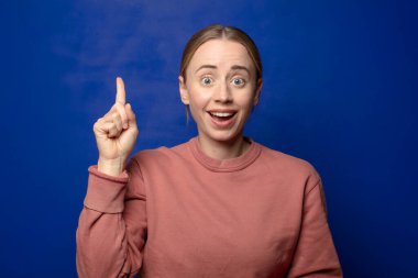 Sarışın kadın, bir fikri fark ettikten sonra mutlu ve heyecanlı bir dahi gibi hissediyor. Neşeli bir şekilde parmağını kaldırıyor.!