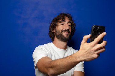 Akıllı telefonu olan genç, sakallı bir adam.