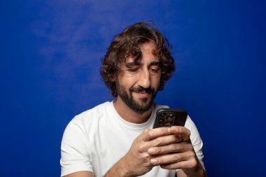 Akıllı telefonu olan genç, sakallı bir adam.