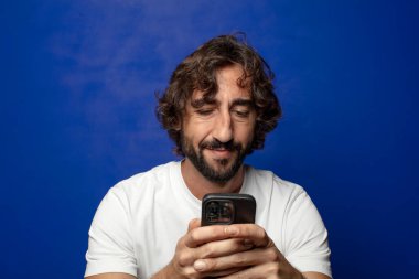 Akıllı telefonu olan genç, sakallı bir adam.