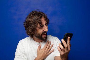 Akıllı telefonu olan genç, sakallı bir adam.