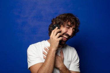 Akıllı telefonu olan genç, sakallı bir adam.