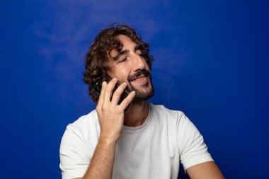 Akıllı telefonu olan genç, sakallı bir adam.