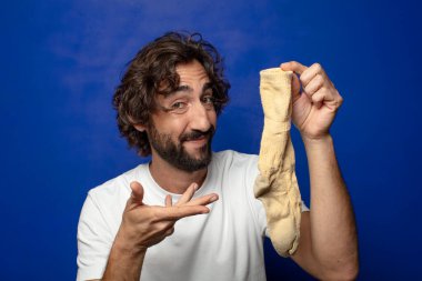 Kirli çorabı olan genç, sakallı bir adam.