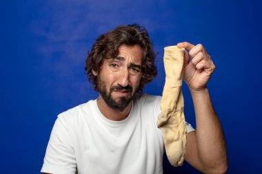 Kirli çorabı olan genç, sakallı bir adam.
