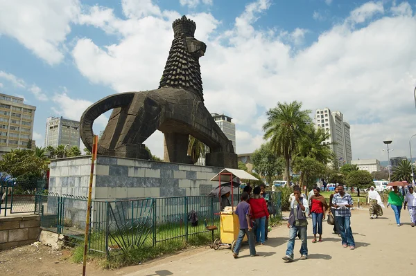 People walk by the street next to the iconic statue of the Lion of Judah in Addis Ababa, Ethiopia. — Stock Photo, Image