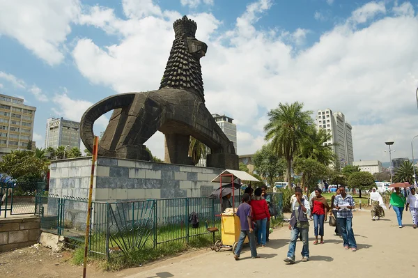 İnsanlar Addis Ababa, Etiyopya'da Yahuda Aslanı'nın ikonik heykelinin yanındaki caddenin yanından yürüyorlar..