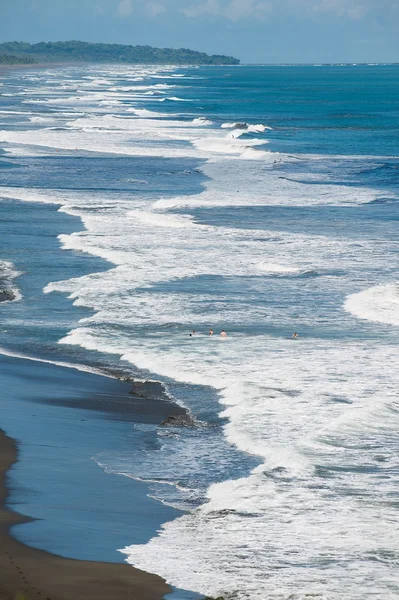 Emberek fürdeni, ő fekete vulkanikus láva strandon, a Csendes-óceán, Costa Rica, Jaco. — Stock Fotó