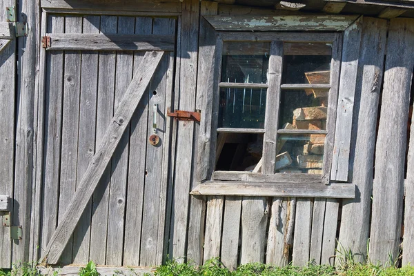 Oude houten schuur met gesloten deur en gebroken raam. — Stockfoto