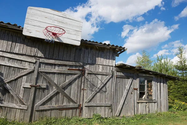 Oude houten schuur met een basketbal hoepel bevestigd. — Stockfoto