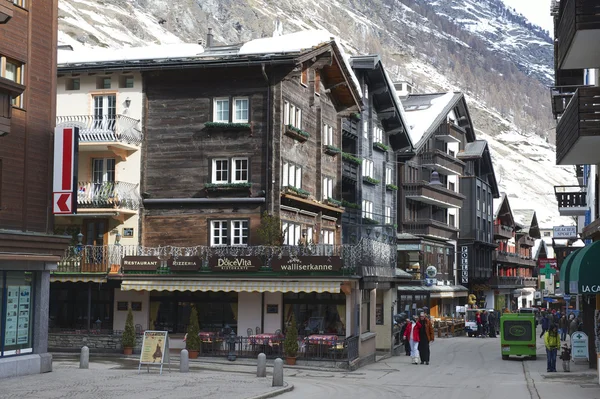 Turisté prozkoumat tradiční dřevěné domy ulici v Zermatt, Švýcarsko. — Stock fotografie