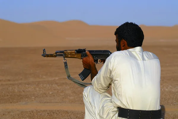 Yemeni man aims with kalashnikov machine gun in the desert, Hadramaut valley, Yemen. — Stock Photo, Image
