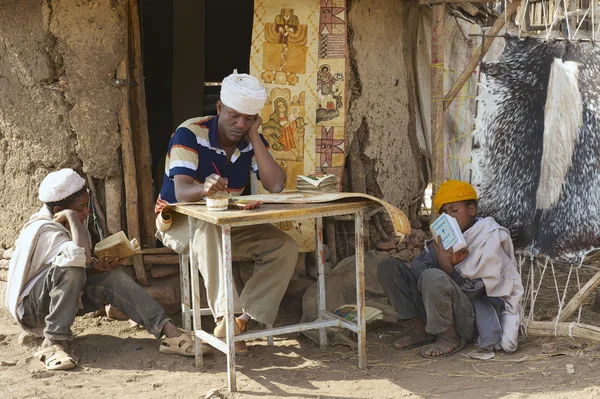 People paint and read at the house entrance in Lalibela, Ethiopia.