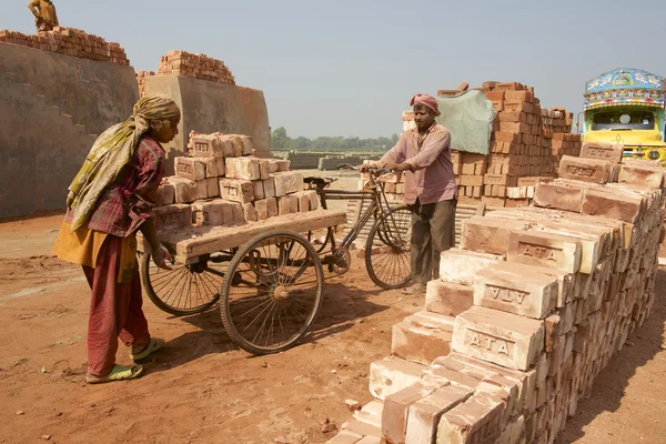Deux travailleurs déplacent des briques dans une usine à Dacca, au Bangladesh . — Photo