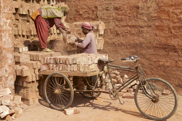 Deux travailleurs chargent un vélo avec des briques à Dhaka, Bangladesh . — Photo