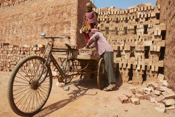 Dois trabalhadores carregam bicicleta com tijolos em Daca, Bangladesh . — Fotografia de Stock