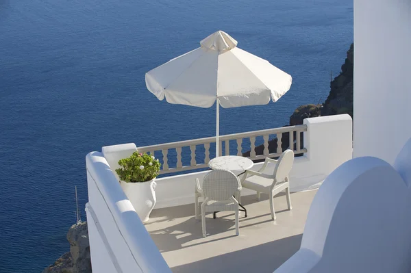 Dwa krzesła pod parasolem z widokiem na morze. Oia Santorini, Grecja. — Zdjęcie stockowe
