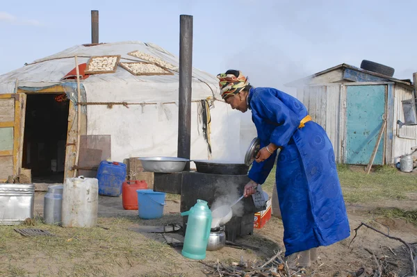 Mujer cocina frente a la yurta en la estepa, Mongolia . — Foto de Stock