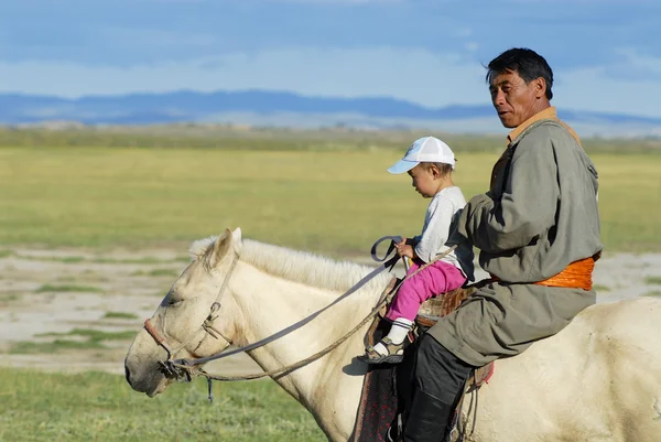 Mongolski mężczyzna jedzie na koniu z dzieckiem ok Harhorin, Mongolia. — Zdjęcie stockowe