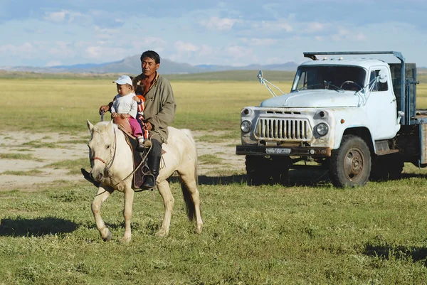 Mongolian man rides on horseback with two kids circa Harhorin, Mongolia. — Stock Photo, Image