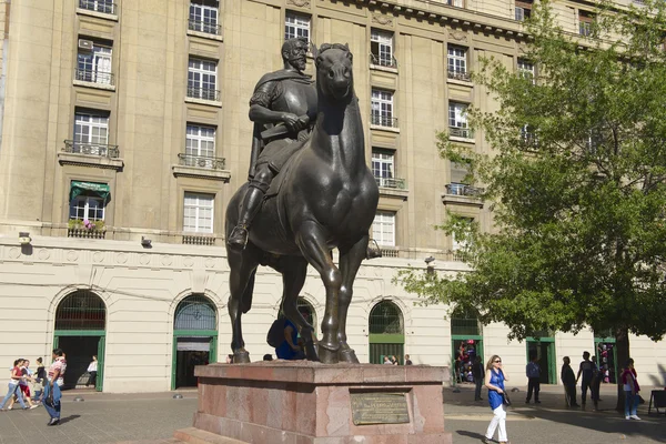 As pessoas caminham perto do monumento equestre para o primeiro governador real do Chile e fundador da cidade de Santiago don Pedro de Valdivia em Santiago, Chile . — Fotografia de Stock