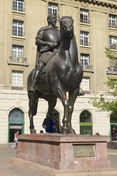 People walk near the equestrian monument to the 1st Royal Governor of Chile and founder of Santiago city don Pedro de Valdivia in Santiago, Chile. — Stock Photo, Image