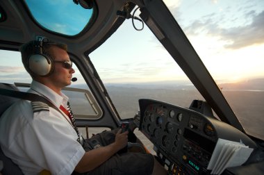 Man pilots helicopter to Grand Canyon at sunset circa Las Vegas, USA. clipart