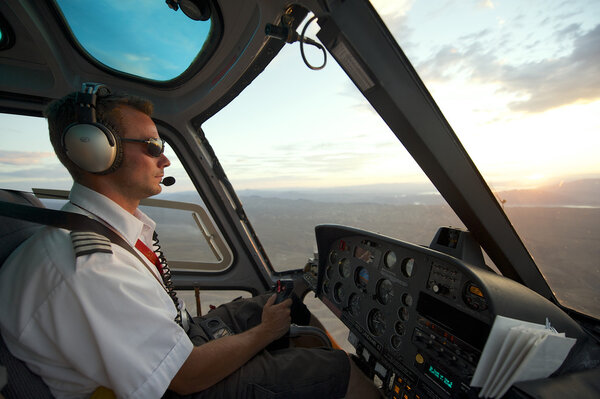 Man pilots helicopter to Grand Canyon at sunset circa Las Vegas, USA.