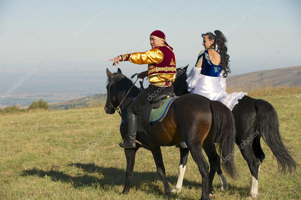 People in national dresses ride on horseback at countryside circa