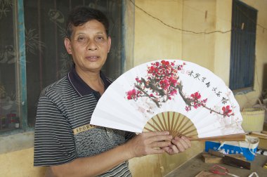 Man holds traditional Chinese fan in Yangshuo, China. clipart