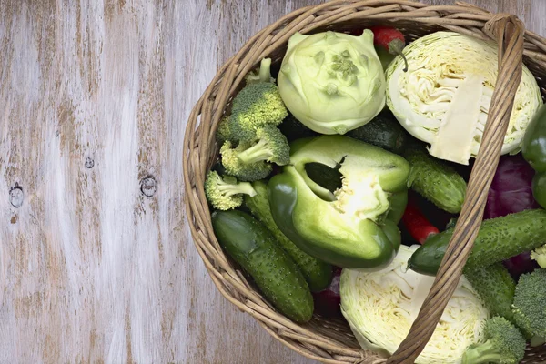 Vegetables in the basket on white painted wooden background: cucumber, broccoli, pepper, cabbage, kohlrabi. — Stock Photo, Image